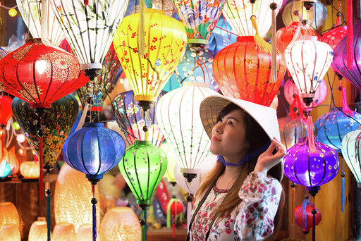 Asian woman tourist is enjoy watching light of lanterns in Old town Hoi An in Vietnam.